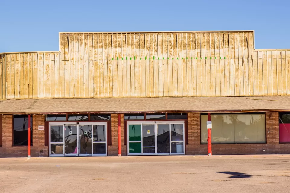 One-story vacant Western-style strip mall with blocked windows.